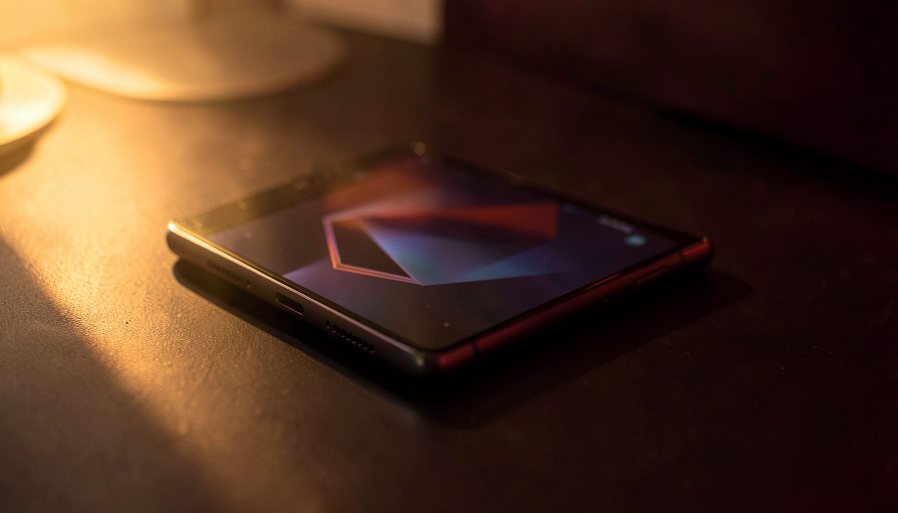 Gaming smartphone with angular design accents resting on a dark desk under warm ambient light